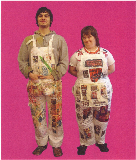 Two artists, a man and a woman stand on a pink background